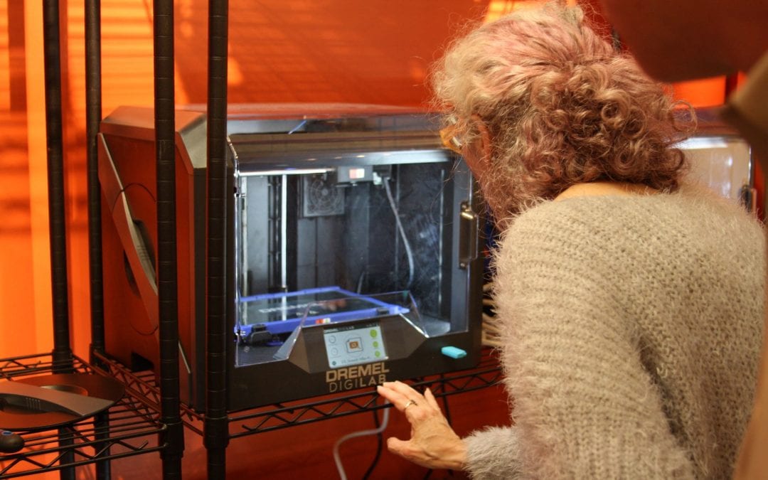 Woman watching a 3D printer print her project.